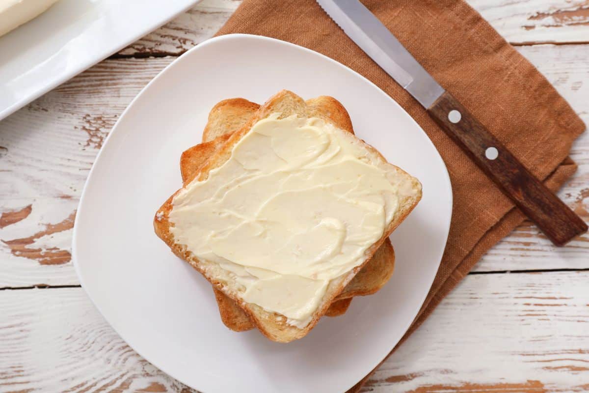 Butter spread on toasted bread slices on a plate.