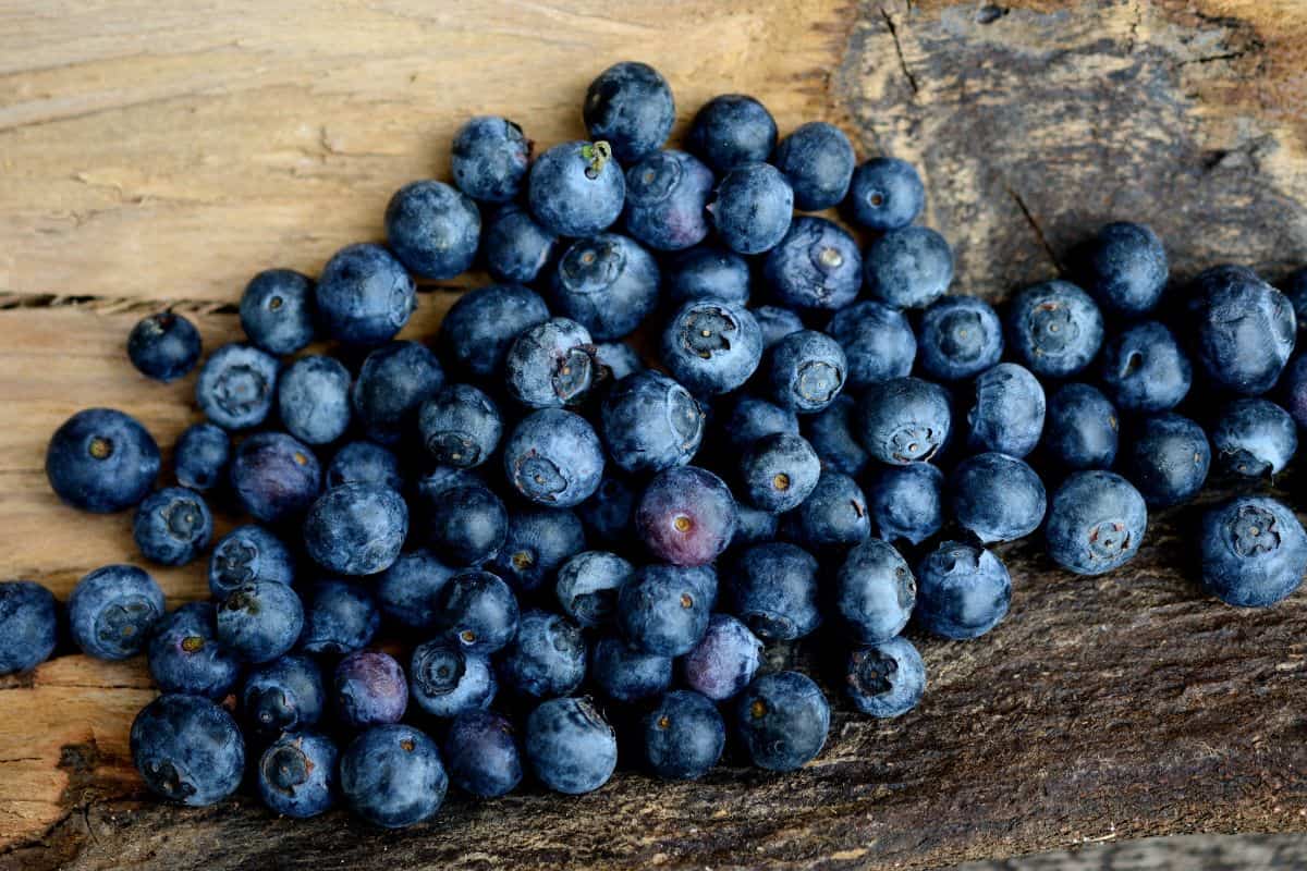 Fresh blueberries scattered across a rustic wooden surface.