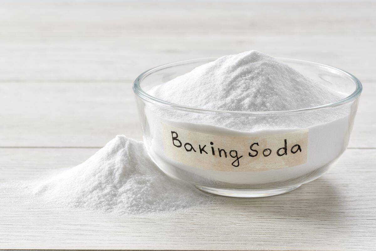 Bowl of baking soda on a white wooden surface.