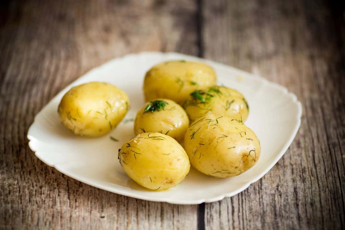 Boiled potatoes garnished with herbs on a white plate.