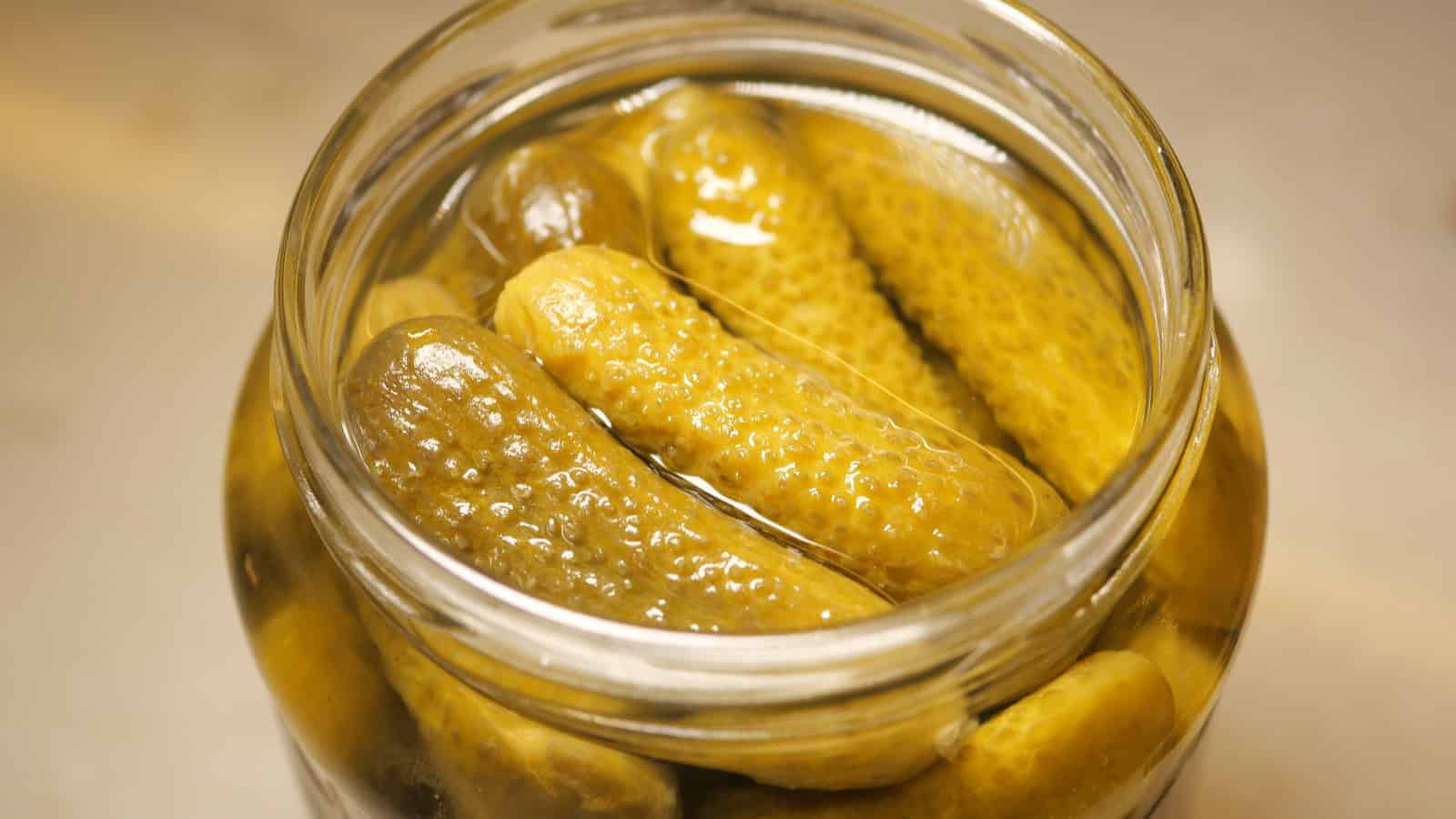 Jar of pickles in brine on a table.
