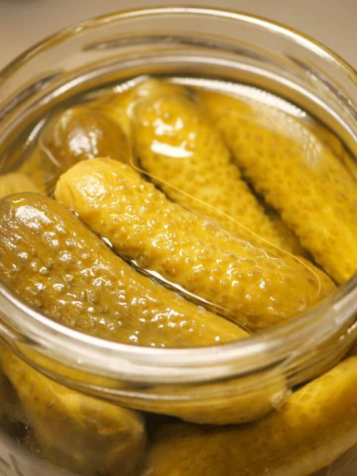 Jar of pickles preserved in brine on a table.