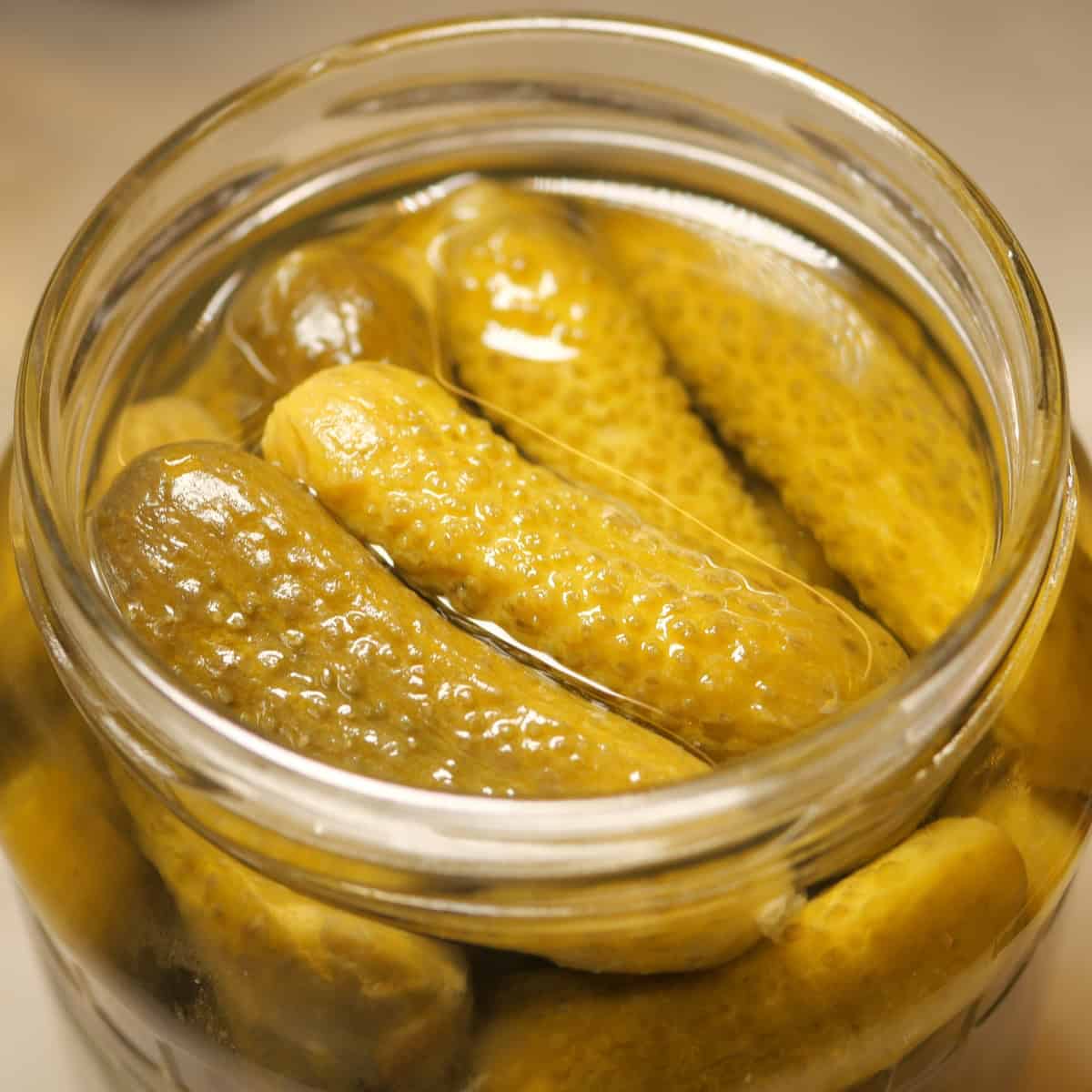 Jar of pickles preserved in brine on a table.