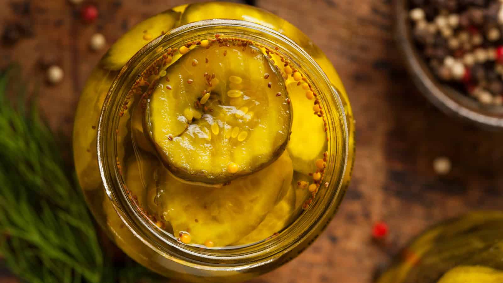 Jar of sliced pickles in seasoned brine.